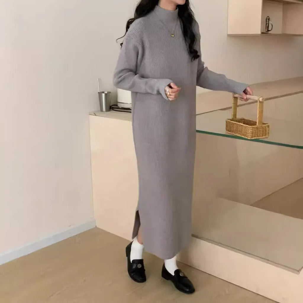 A woman wearing a beige turtleneck knitted dress with long sleeves and a high waist.