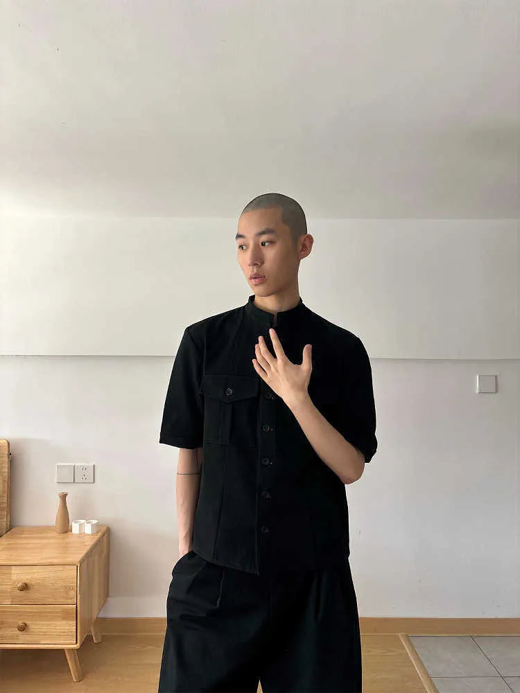 A black handmade half sleeve shirt with a shirt collar, shown on a hanger.