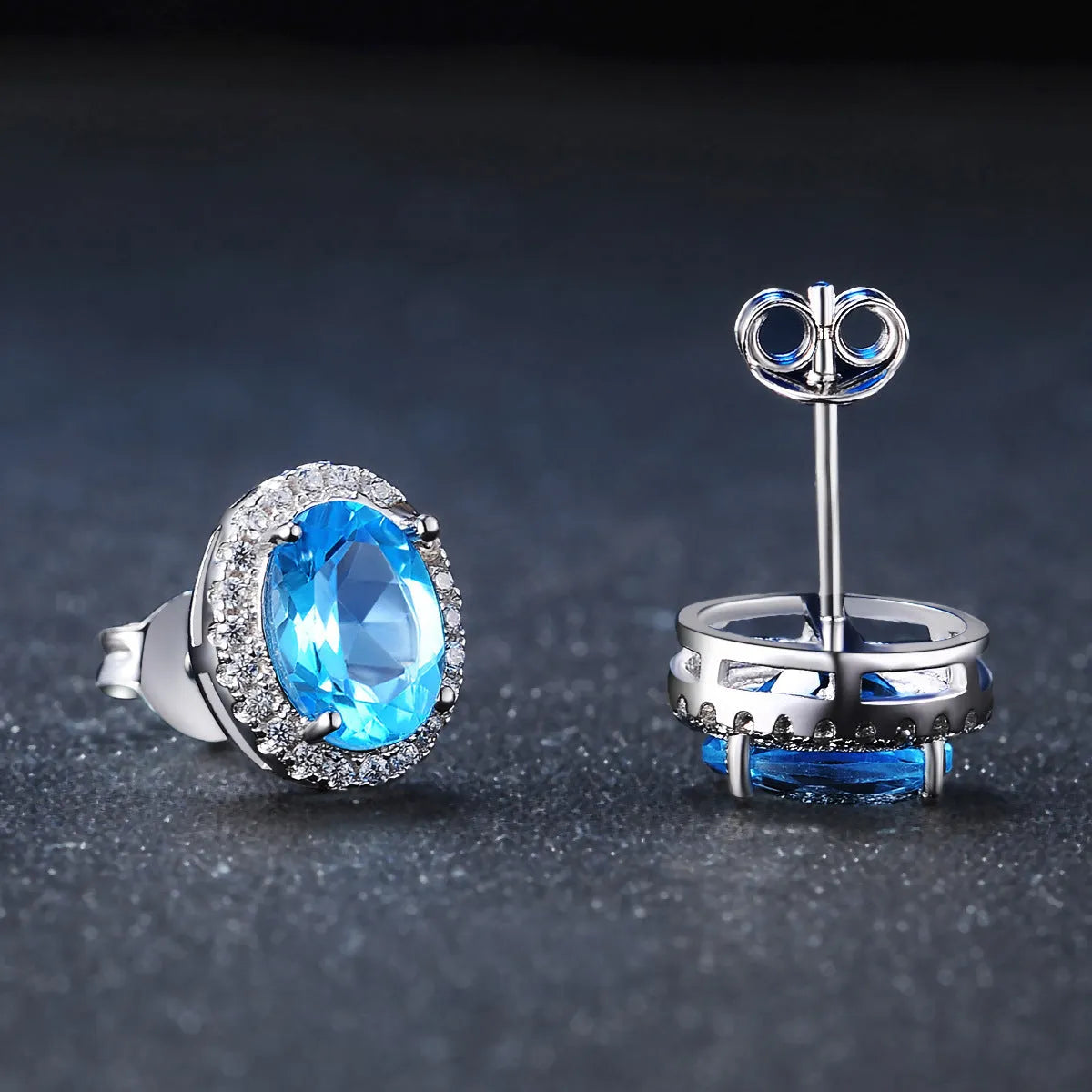 A four-piece women's sterling silver jewellery set with blue topaz gems, showing geometric earrings, ring, pendant, and necklace.