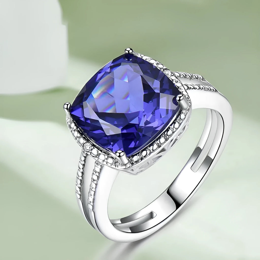Women's sterling silver ring with a blue tanzanite gemstone on a finger.