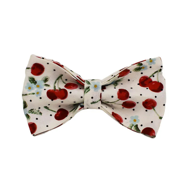 Red cherry printed cloth dog collar set with light gold buckle, matching leash, bow, vest, and bag.