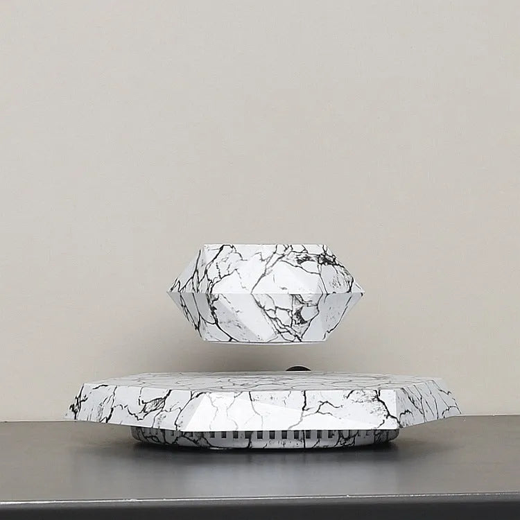 Marble-coloured levitating plant pot floating above magnetic base with small plant rotating