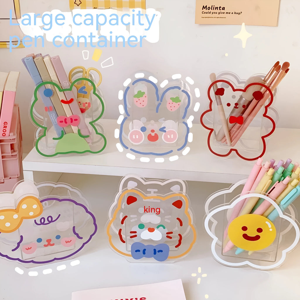 Clear square acrylic storage box with cute decorative design, shown holding pens and small items on a desk.