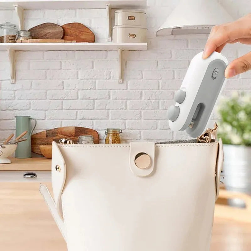 Blue handheld USB rechargeable heat sealer and bag cutter on a kitchen counter.