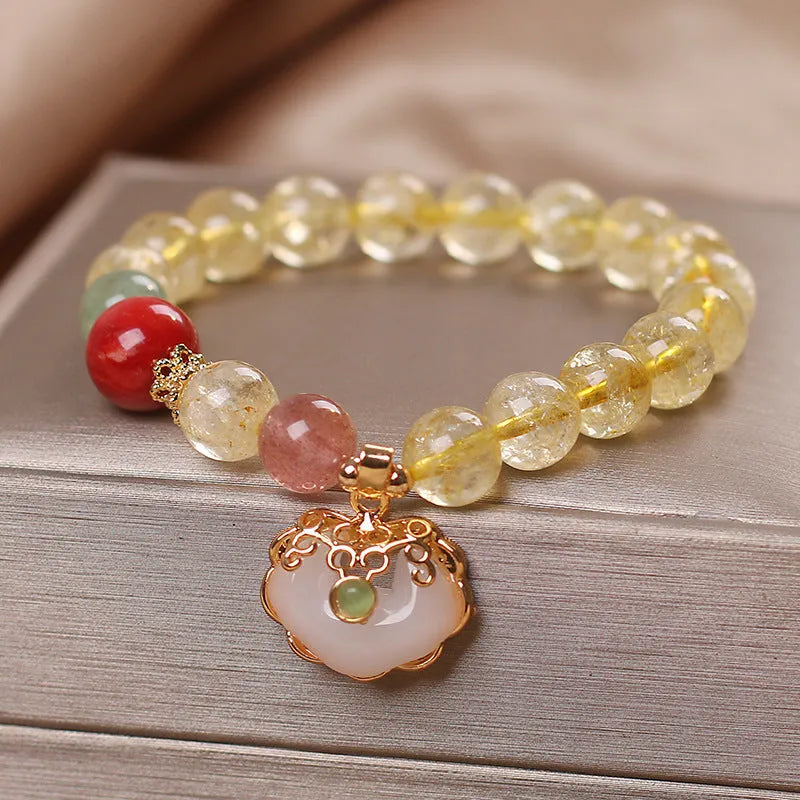 Close-up of a women's alloy bracelet with a yellow citrine jade ruyi pendant.
