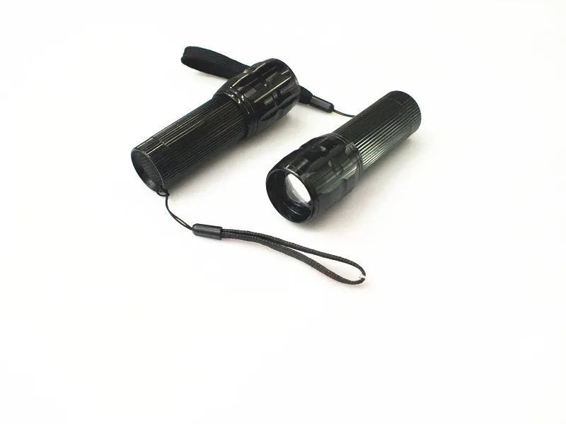 Black mini LED flashlight with telescopic head and tail push button switch on plain background