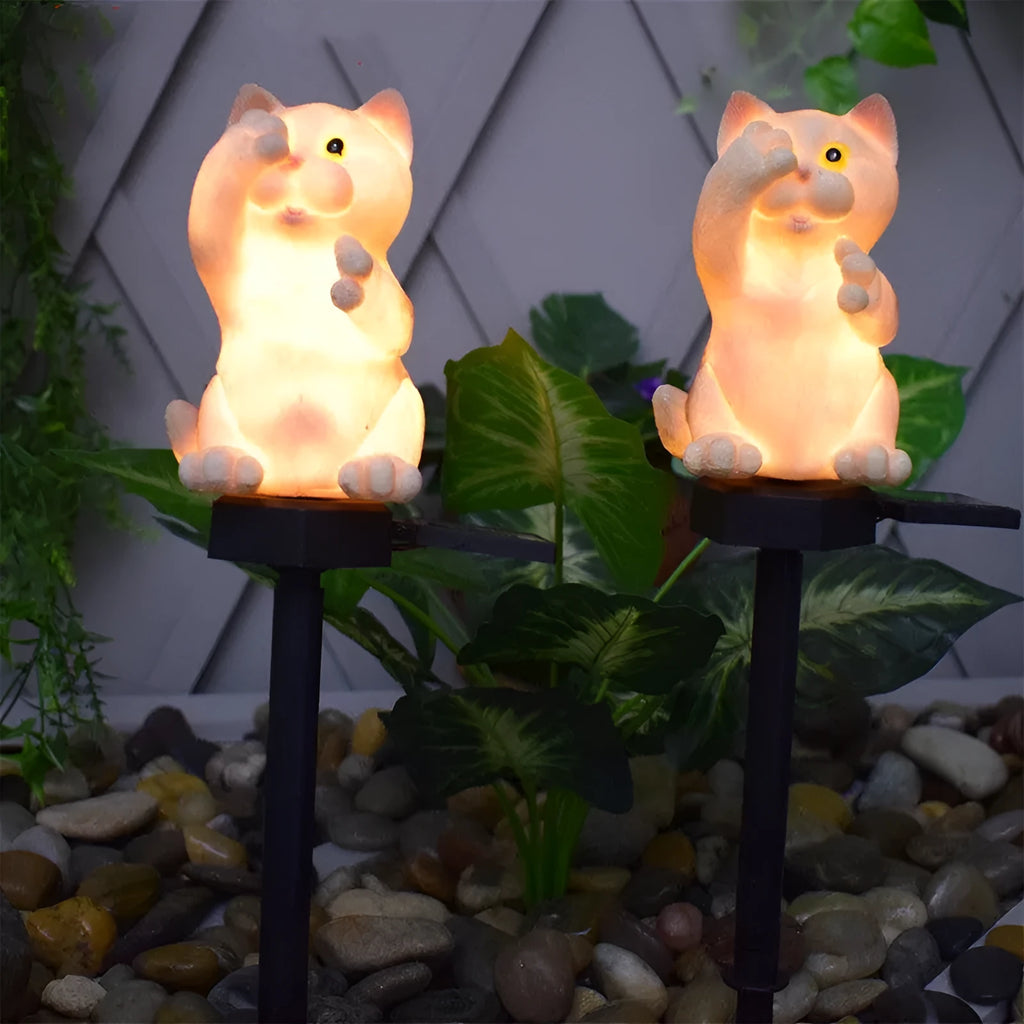 Brown resin solar-powered cat lawn light with LED illumination in a garden setting.
