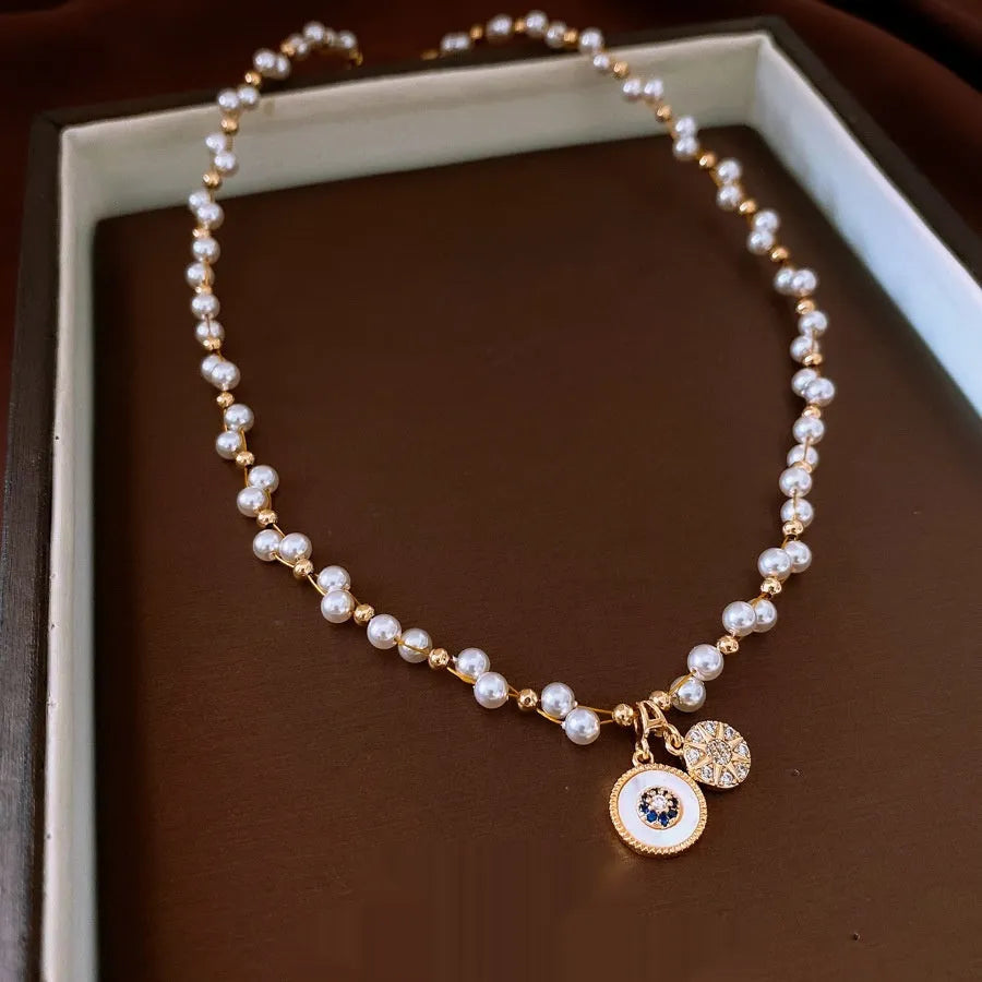 Gold-white electroplated necklace with round imitation pearl and zircon pendant on an adjustable clavicle chain.