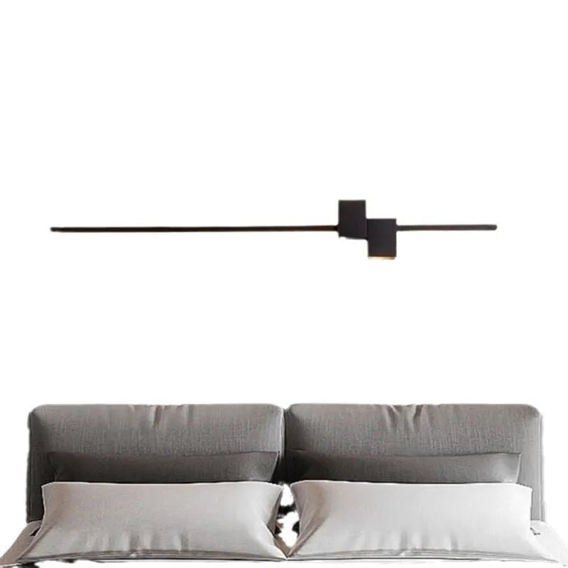Modern minimalist wall lamp black 80cm length installed above a bedside table with warm low-voltage light
