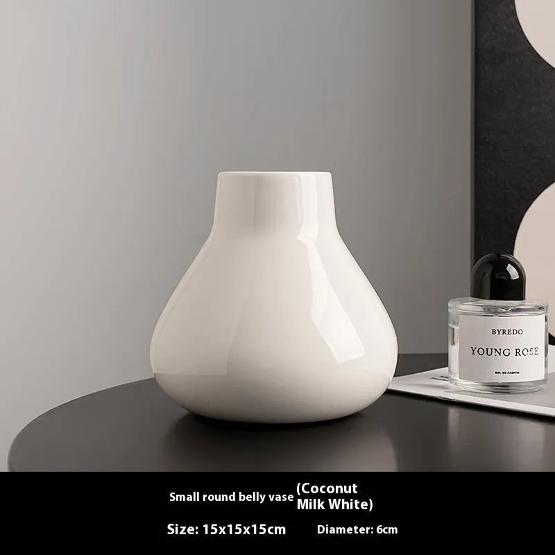 Black ceramic round belly vase with white orchid flowers on wooden shelf