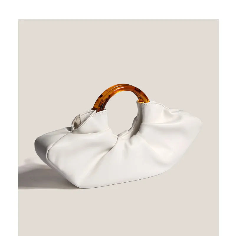 Niche horn bag in black or white PU leather with acrylic ring handle and fold detail for daily matching.