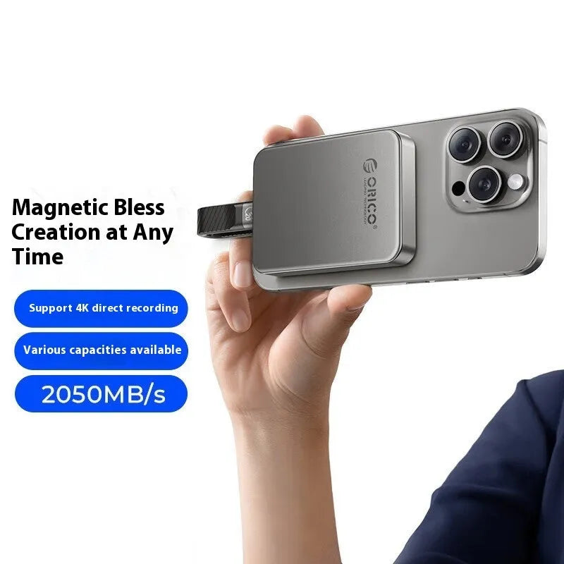 Grey magnetic mobile solid state drive with attached magnetic ring and USB C cable on a white surface.