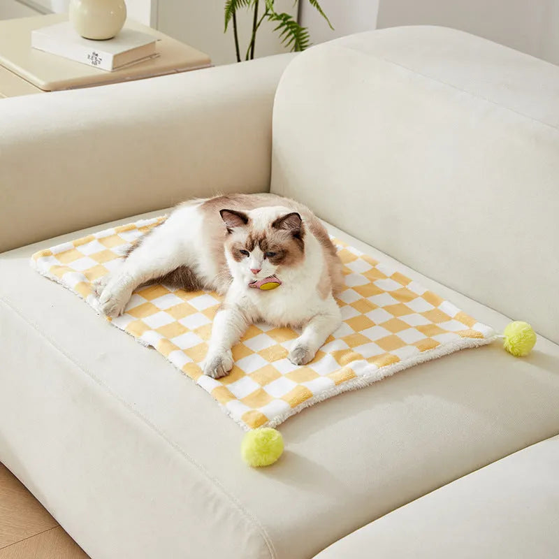 Green plaid pattern soft fleece pet blanket with fur ball decoration on a sofa