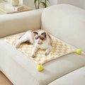 Green plaid pattern soft fleece pet blanket with fur ball decoration on a sofa
