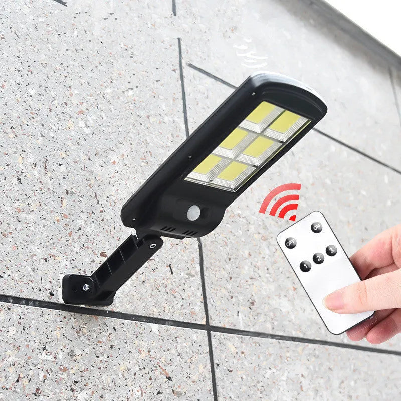 Black solar-powered outdoor motion sensor light mounted on a wall.