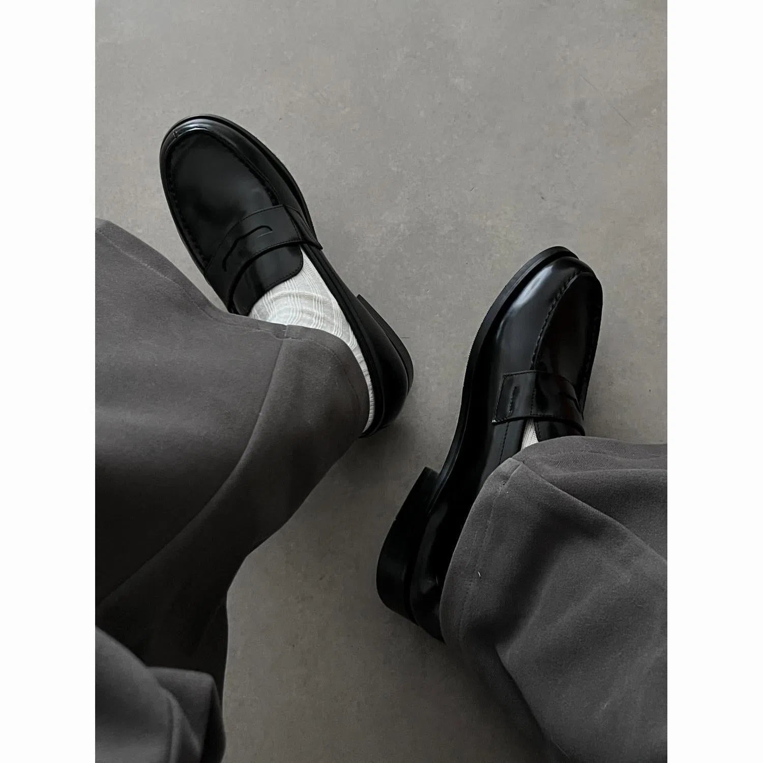 Men's black British-style slip-on leather loafers with stitched seams and vulcanised rubber sole on a plain background