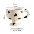 Handmade irregularly shaped ceramic mug in a solid colour, shown on a table.