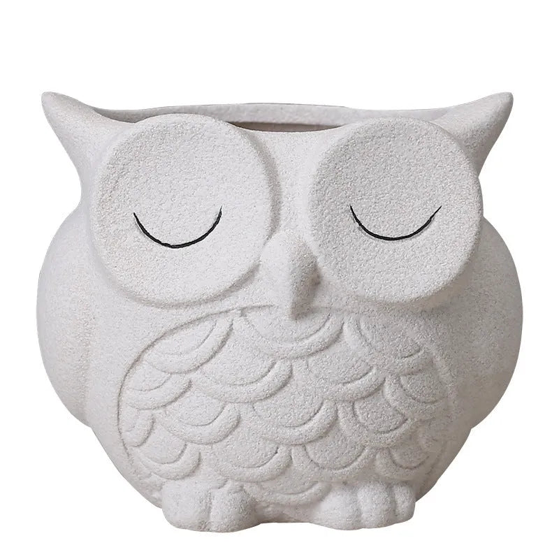 Handmade frosted ceramic owl succulent pot in pastel colour on a wooden surface.
