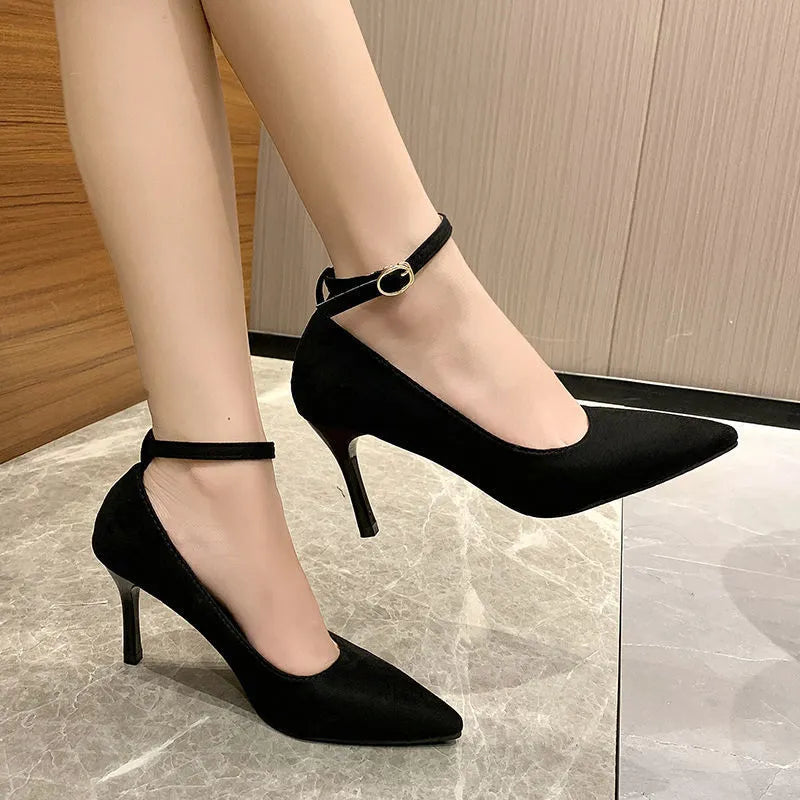 Women's black stiletto pump with skull pattern and buckle decoration on a white background.