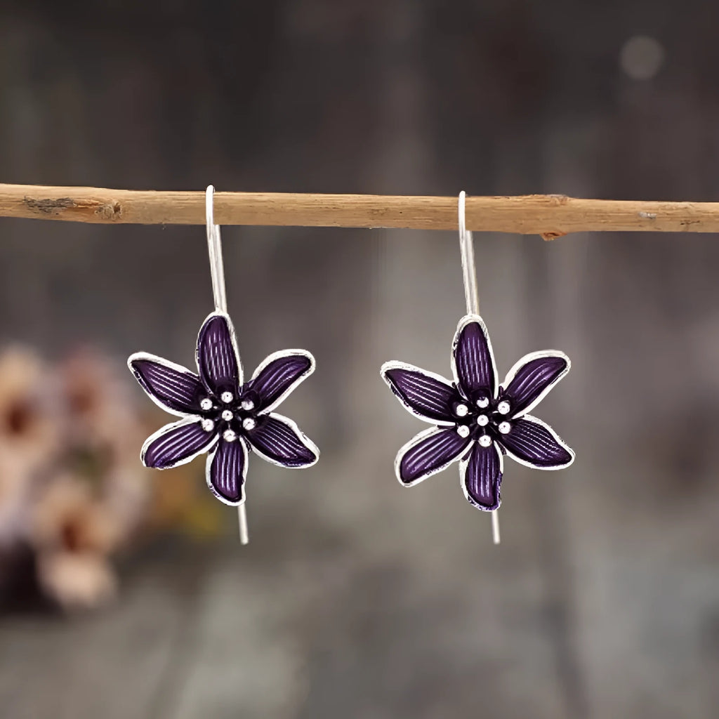 A pair of purple flower-shaped alloy drop earrings with a retro design on a white background.