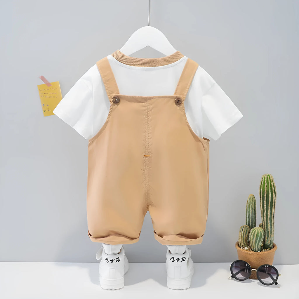 Baby wearing yellow cotton short-sleeved overalls with cartoon design and adjustable straps.
