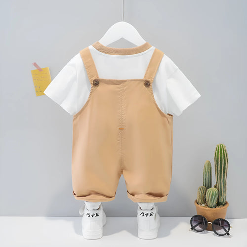 Baby wearing yellow cotton short-sleeved overalls with cartoon design and adjustable straps.