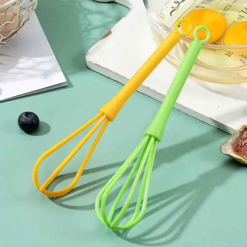 Plastic mini manual eggbeater in green for stirring batter in a kitchen