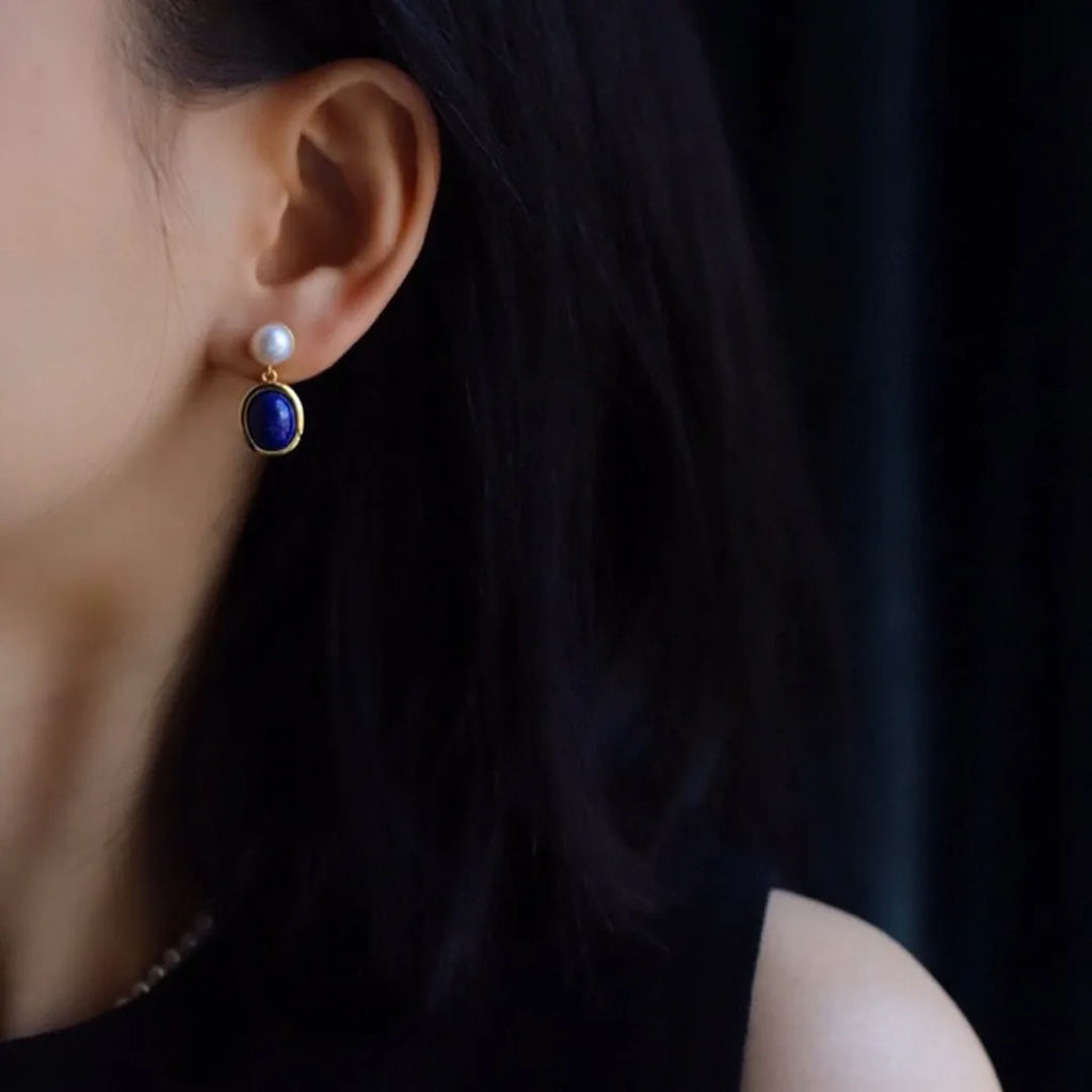 A pair of simple 925 silver stud earrings with a blue lapis lazuli pearl and auspicious patterns.