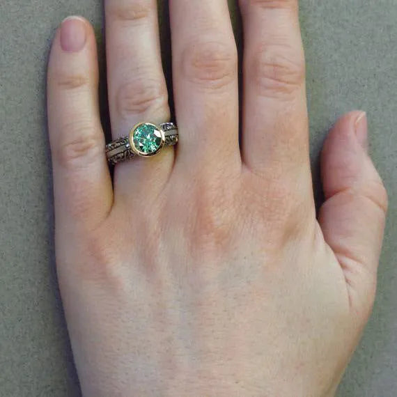 Flower-shaped gold-plated vintage ring with green gemstone and colour separation design on finger