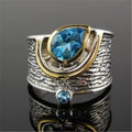 Blue zircon drop-shaped ring with Chinese style rhinestone inlay, shown on a finger.