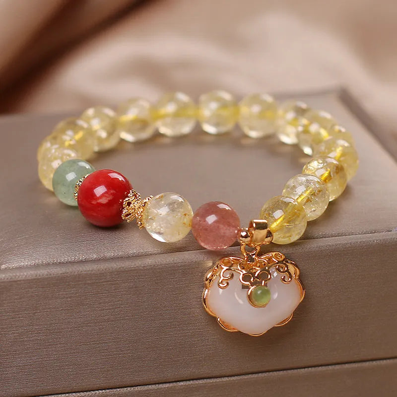Close-up of a women's alloy bracelet with a yellow citrine jade ruyi pendant.