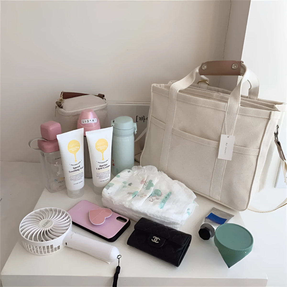 Beige canvas crossbody mommy bag holding baby bottles and wipes on table