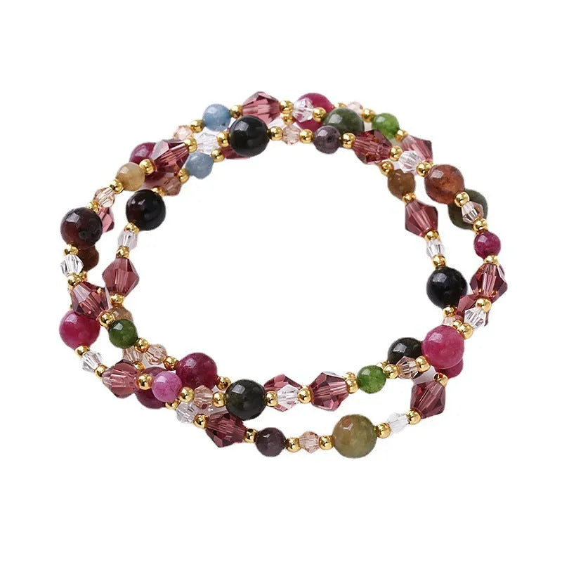 Close-up of a three-ring women's bracelet with tourmaline, strawberry quartz, and amethyst crystals on an adjustable rope.