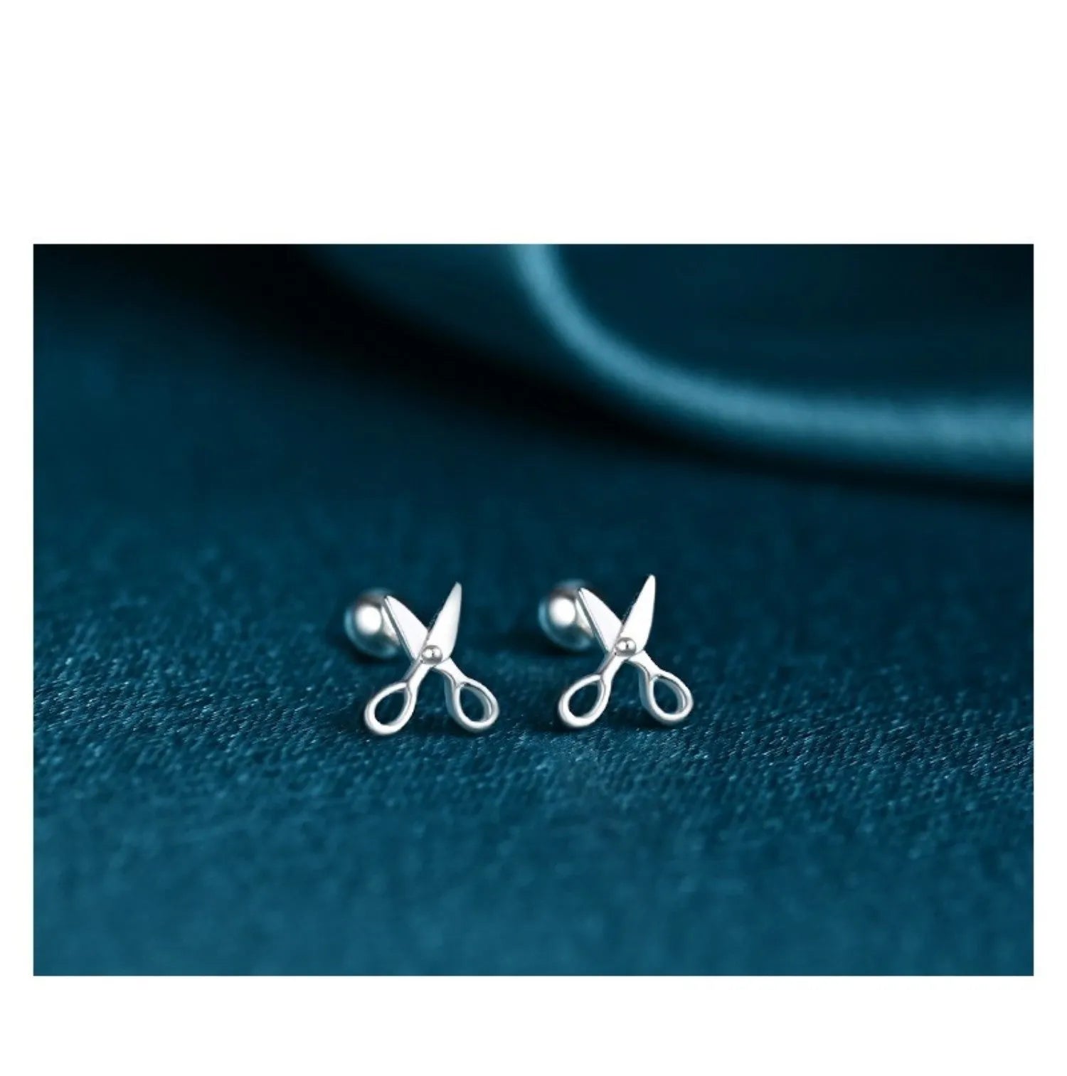 A pair of pure silver screw-back earrings for women with a mini scissors design on the fastening.