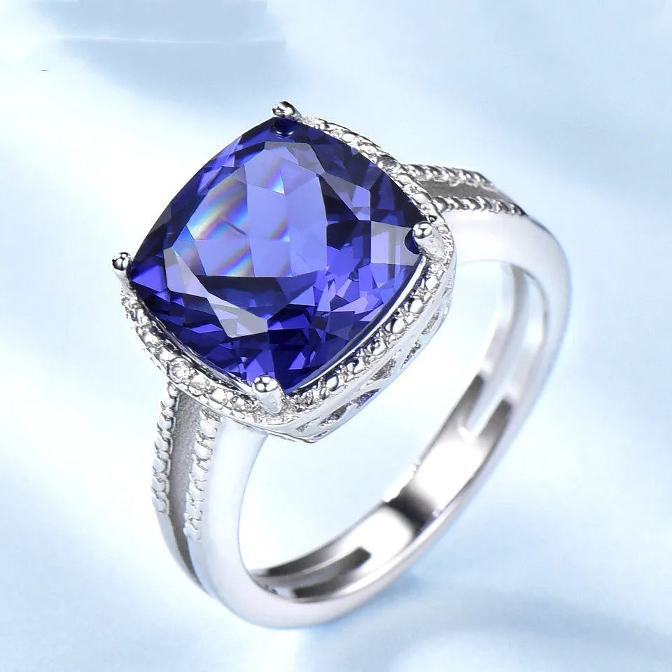 Women's sterling silver ring with a blue tanzanite gemstone on a finger.