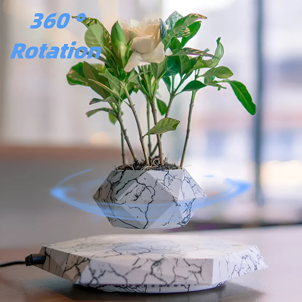 Marble-coloured levitating plant pot floating above magnetic base with small plant rotating