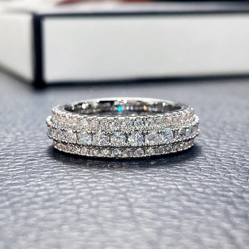 Geometric triangular zircon inlay ring in white gold finish on a finger.