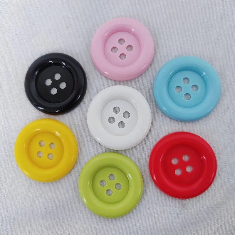 Assorted oversized round plastic buttons in black, white, red, blue and yellow on a white background.