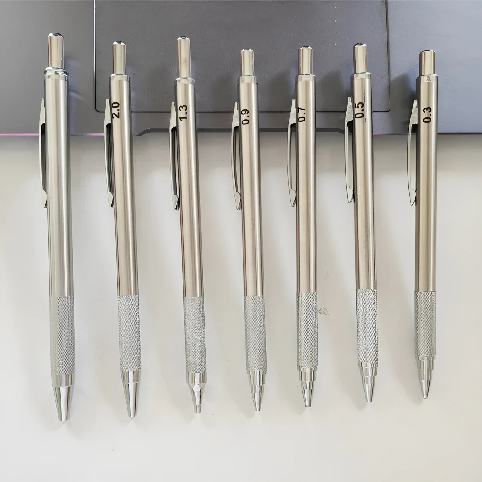 Silver metal mechanical pencil with clip, shown with compatible lead refills in sizes 0.5mm and 2.0mm.
