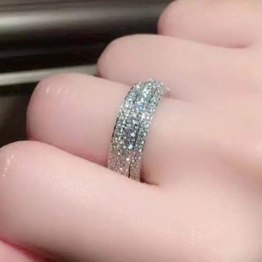 Geometric triangular zircon inlay ring in white gold finish on a finger.