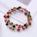 Close-up of a three-ring women's bracelet with tourmaline, strawberry quartz, and amethyst crystals on an adjustable rope.