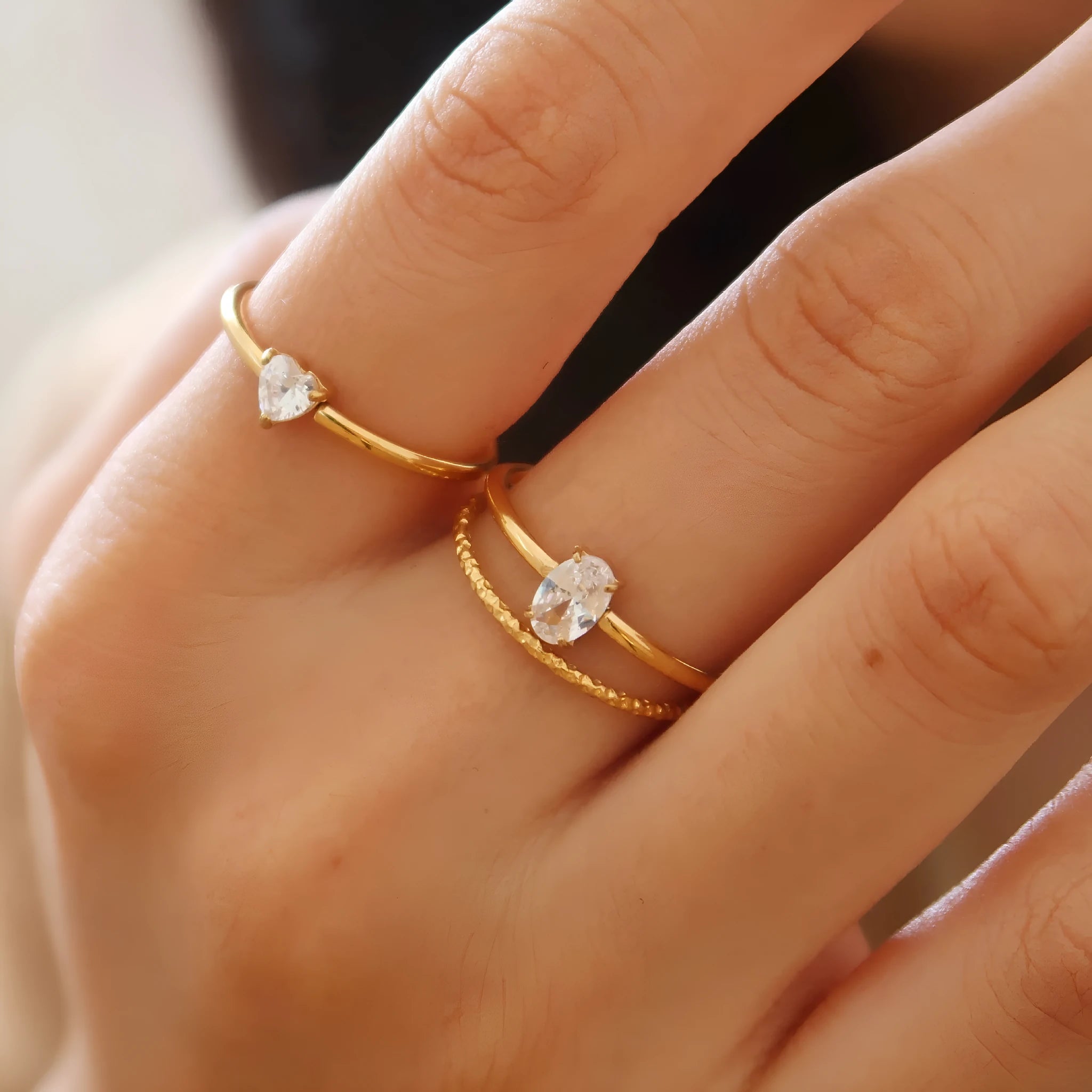 Golden love heart and oval stainless steel ring for women on a white background.