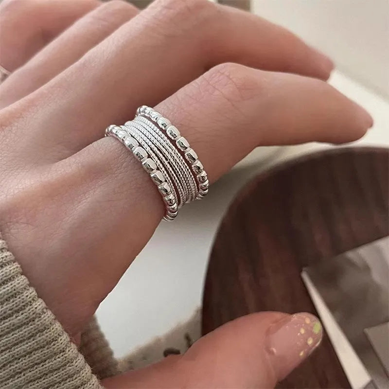 Copper geometric ring with woven twisted multilayer design and adjustable opening.