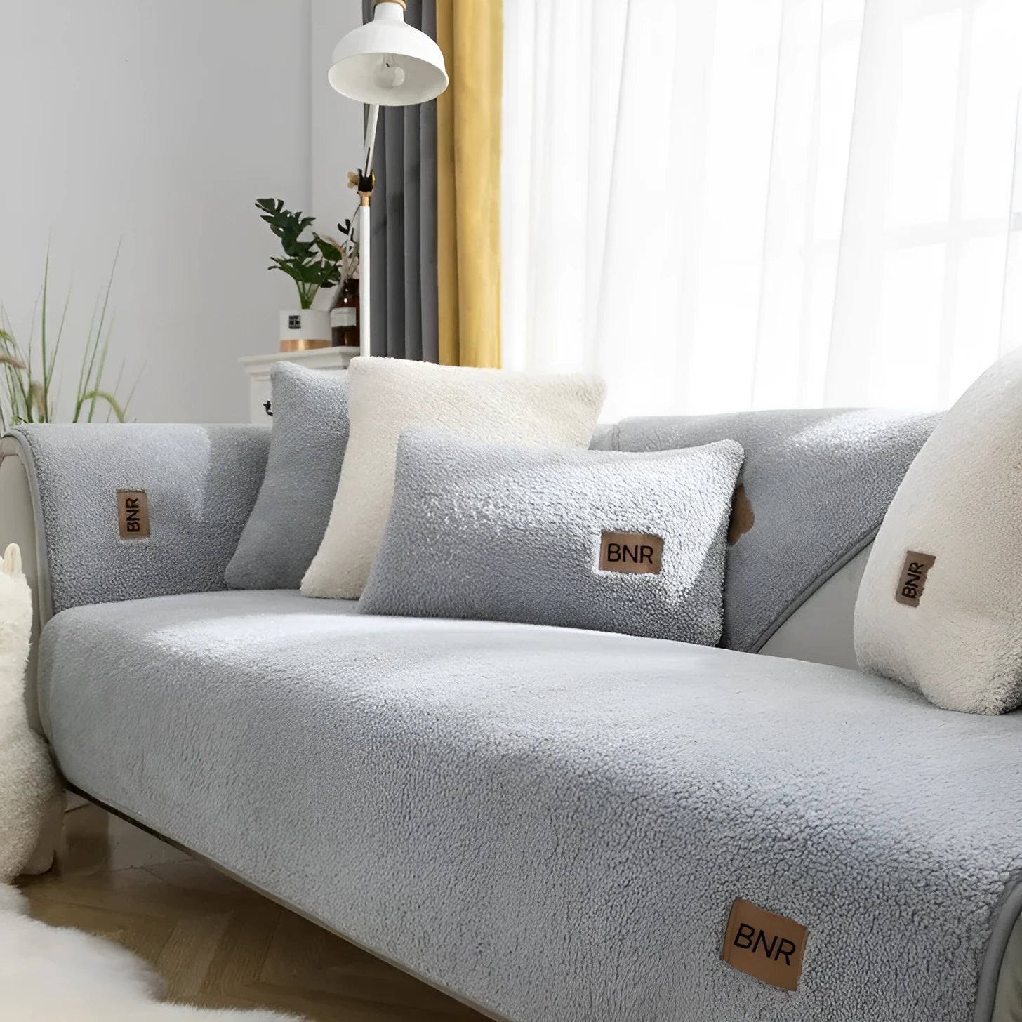 Lambswool sofa cover in blue on a grey sofa, showing simple solid colour and cloth liner style.