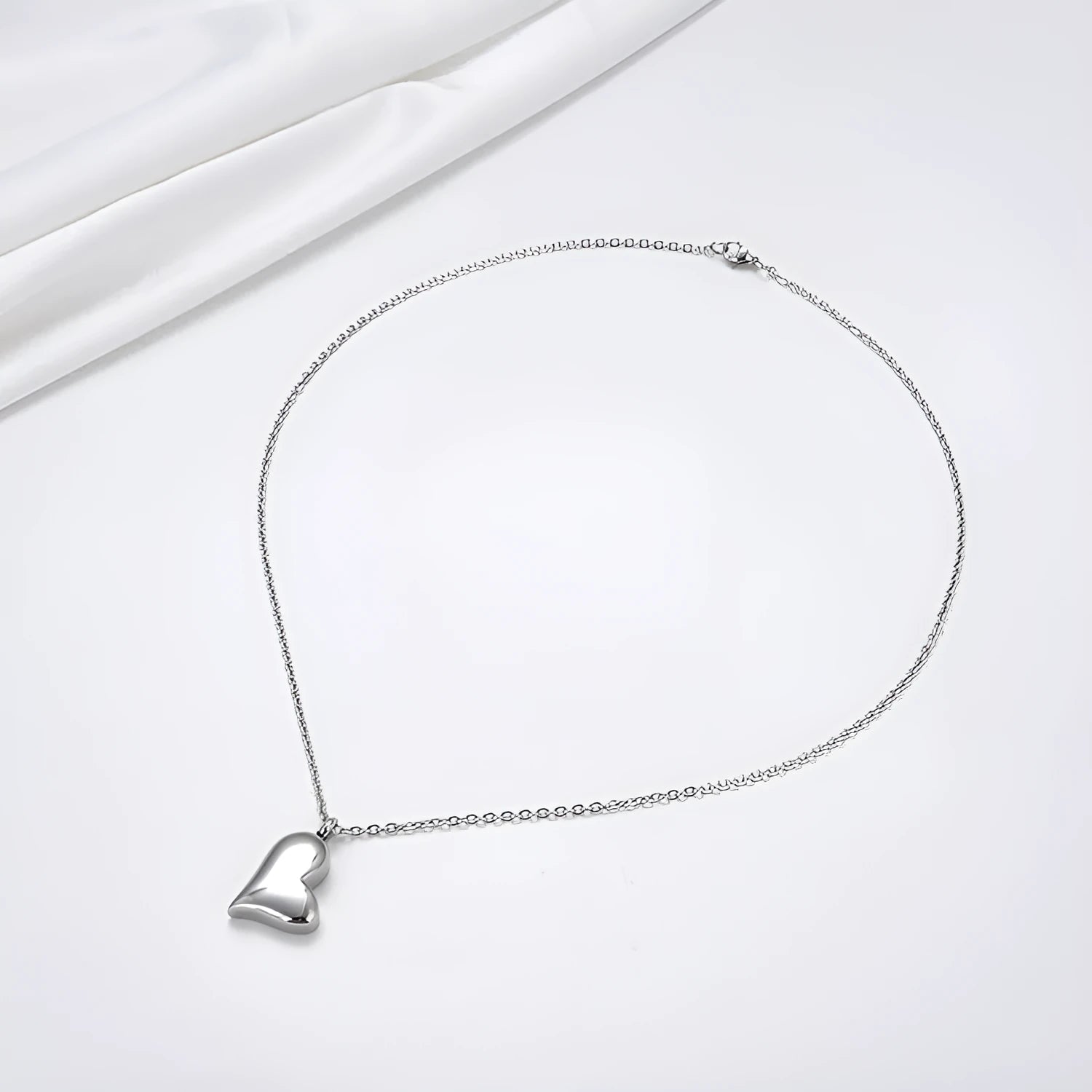 Silver curved peach heart pendant necklace on a stainless steel chain with an extension.