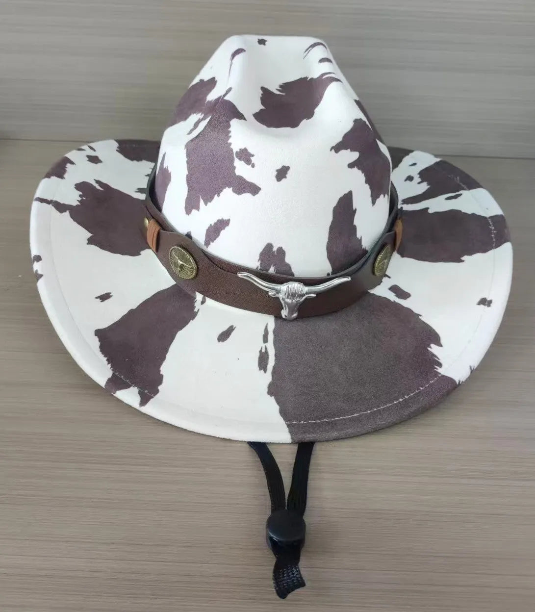 Brown leather velvet curved edge Western cowboy hat with a conical crown on a wooden surface.