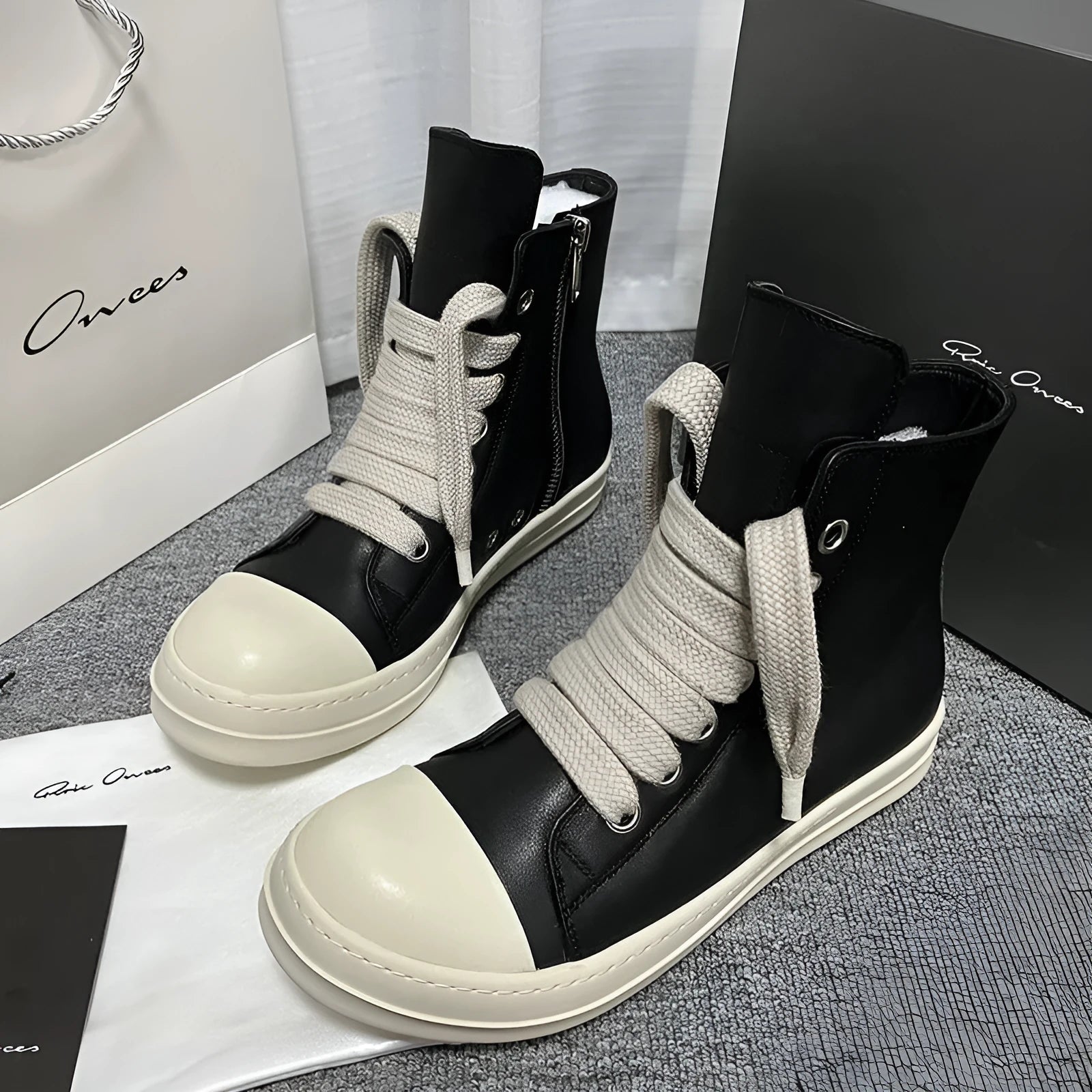 Black high-top leather shoes with a side zip and round toe on a rubber sole.