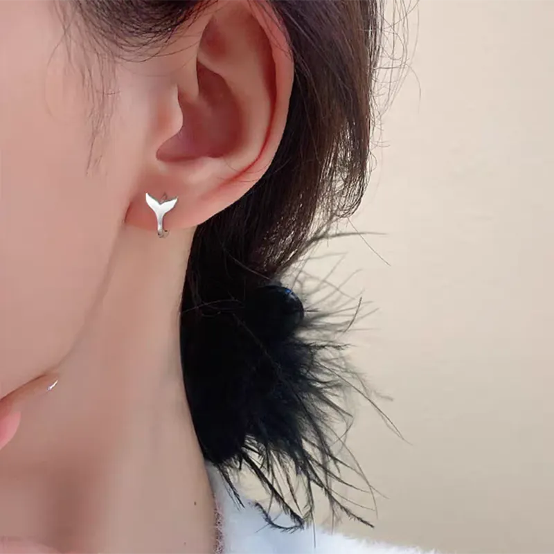 A pair of simple women's fishtail earrings in electroplated copper, shown in white gold colour.