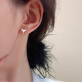 A pair of simple women's fishtail earrings in electroplated copper, shown in white gold colour.