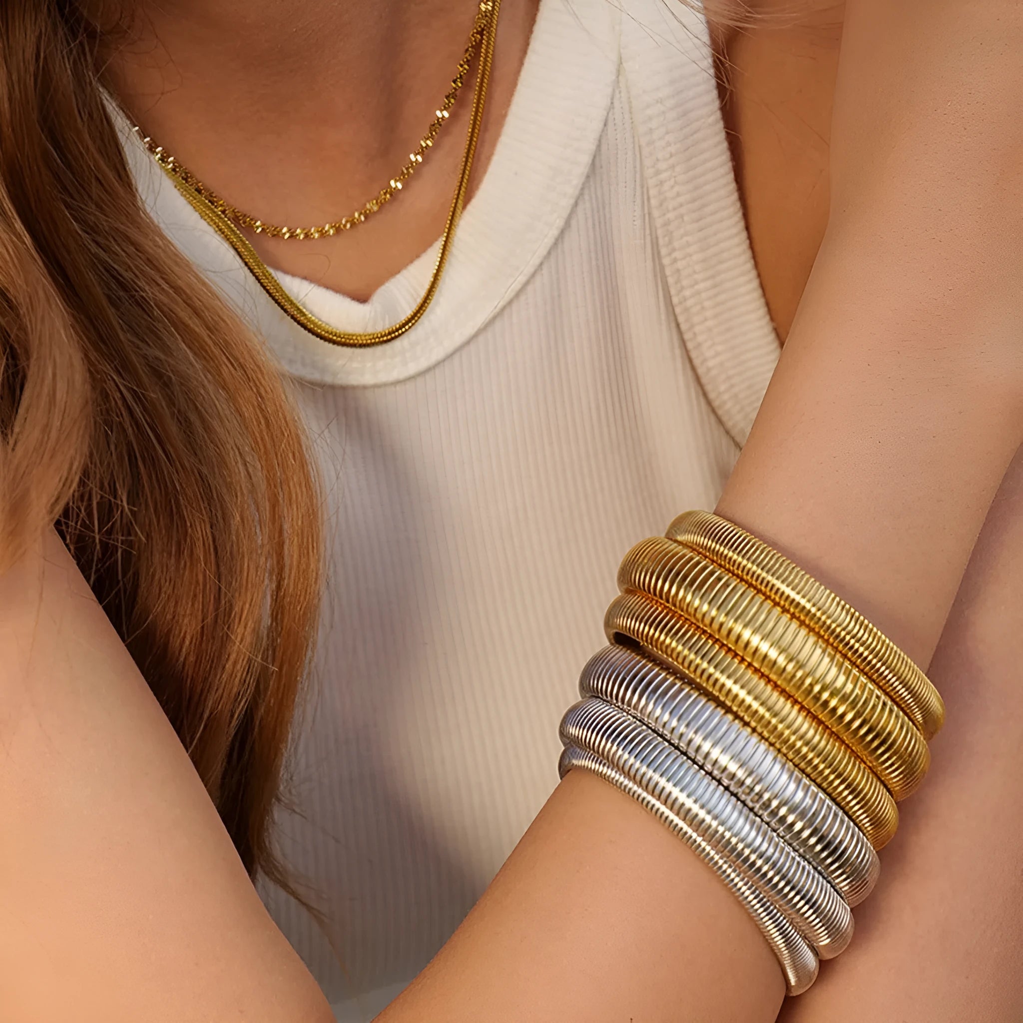 Women's titanium steel bracelet with vertical stripe ring design in gold plating, shown on a wrist.
